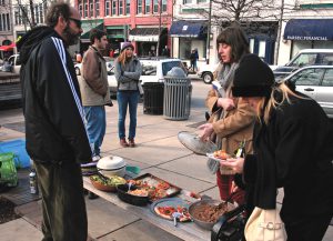 Student volunteers from a food donation group, Food Not Bombs, prepare meals for the homeless in a campus kitchen and bring them to downtown Asheville to distribute.