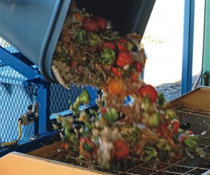 A cart lifter is used to unload food waste into the hopper of the mixer of a new in-vessel composter installed at Cedar Creek Corrections Center.