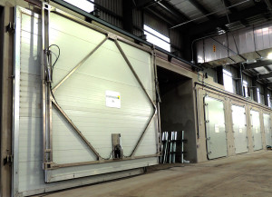 The four in-vessel composting tunnels (one shown on left in photo) are next to one of the banks of digesters (to the right). Content of two digesters fills one composting tunnel.