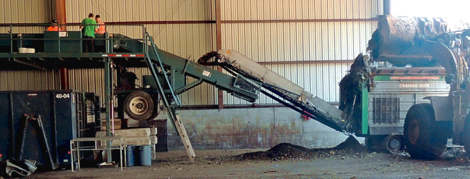 Following processing in a Komptech Crambo slow speed shredder (right), residential SSO is conveyed to a picking line and then passed under a strong magnet. Sorters achieve about 70 to 80 percent contaminant removal.