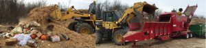 A Rotochopper (right) grinds wooden crates, ammo boxes, dimensional lumber and other waste wood to use as amendment for food waste composting. Food scraps are collected in compostable bags (visible in photo, left). 