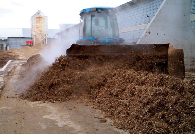 Manure and locally available carbon sources (below) are mixed on concrete pads next to the high-rise houses. A Brown Bear PTO composting aerator attached to a farm tractor (left) is used to blend the feedstocks and agitate and aerate the composting piles. 